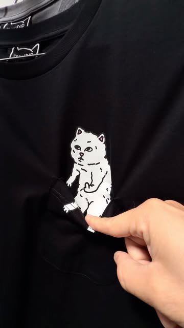 Lord Nermal peeking from a black pocket tee